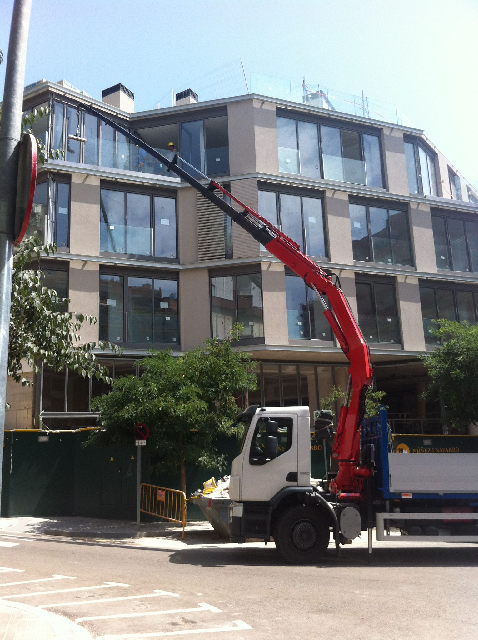 Camión grúa de Trans-Grúas Palazón instalando vidrio en fachada de edificio